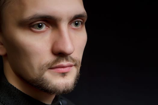 face of the young unshaven man in a black background