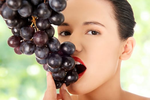 beautiful sensual brunette eating dark grapes