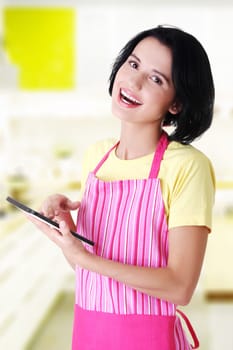 young woman in pink apron using tablet computer