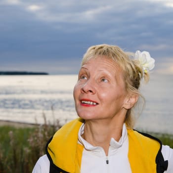 Woman looks at a cloudy sky at the sea