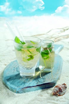 Refreshing mojito cocktail served at the seaside on a tropical beach on an old wooden board