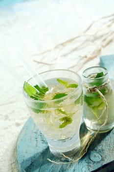 Ice cold mojito cocktail with tangy lime and mint served in a glass with an accompanying carafe