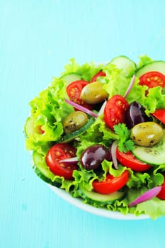 Plate of fresh mixed salad with olives, crisp leafy lettuce, tomato and cucumber for a healthy low calorie meal