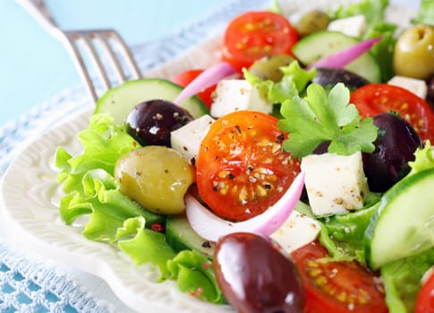 Delicious Greek salad with feta cheese, olives, tomato, cucumber and crispy lettuce garnished with chopped parsley