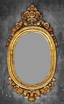 Old-fashioned oval gilt frame for a mirror on a gray concrete wall