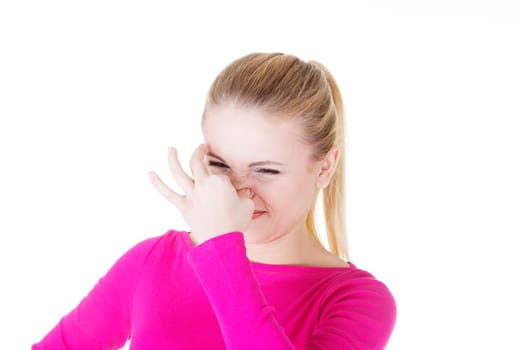 Woman covers nose with hand showing that something stinks, isolated on white