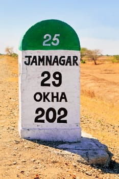 Horizontal color landscape of the 29 kilometers to Jamnagar direction milestone of the Gujarat state highway in India. Incorporates marker for Okha 202 kms, capture location a barren part of Gujarat on the state highway 25 - SH25