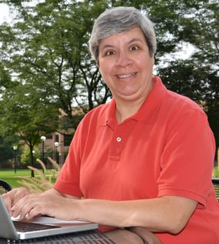 Happy middle-aged woman at table with laptop
