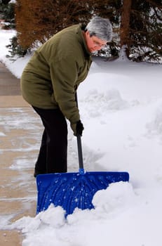middle aged woman shoveling snow off sidewalk