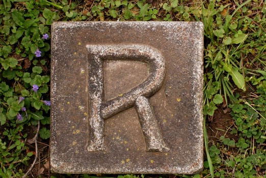 Block with letter R stone, in ground