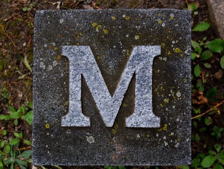 Block with letter M stone, in ground