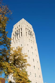 carillon bell tower with clock against blue sky - fall