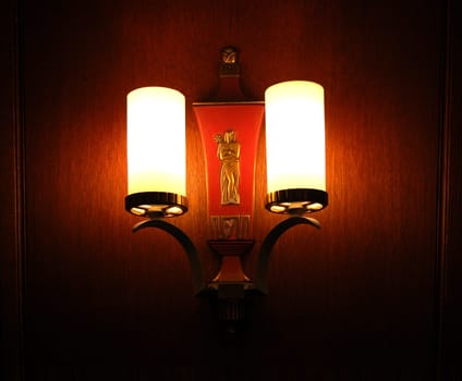 Vintage wall sconce in darkened room, with sculpture