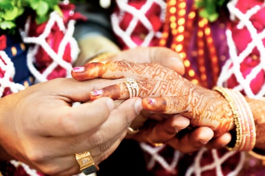 Horizontal color capture taken at a hindu wedding in Surat India. Photo session after the ceremony of the happy groom placing the wedding ring on the brides finer for the cameras. Life is just about to begin.