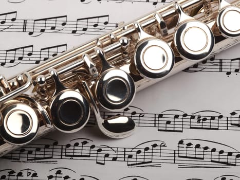 .A used flute rests across an open musical score. Only one line of music is in focus.