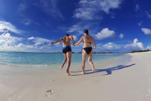 happy young couple have fun and relax at summer vacation on background maldives travel location and beautiful white sand beach