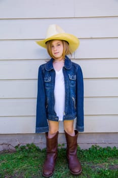 Little kid girl pretending to be a cowboy with father boots and hat