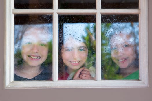three sister friends looking through the window with a pup and raindrops