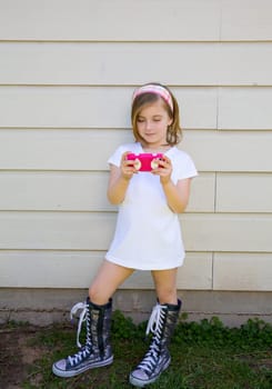 blond little fashion kid girl playing with pink smartphone