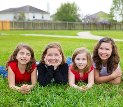 Children girls group lying on lawn grass smiling happy together in a row
