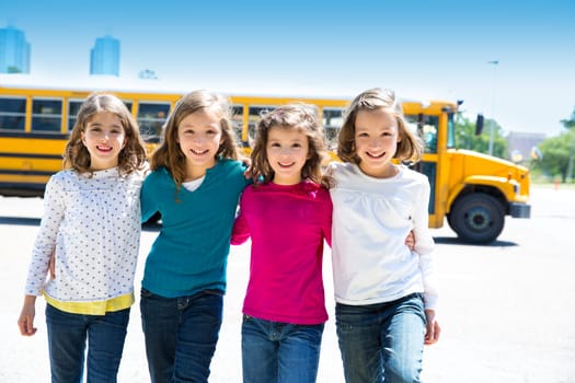 school girls friends sisters in a row walking from yellow school bus lot