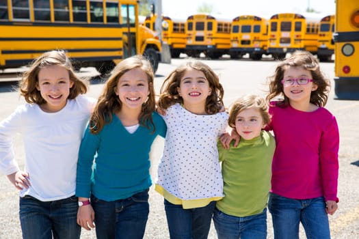 school girls friends sisters in a row walking from yellow school bus lot