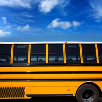 American typical school bus side view on blue sky day