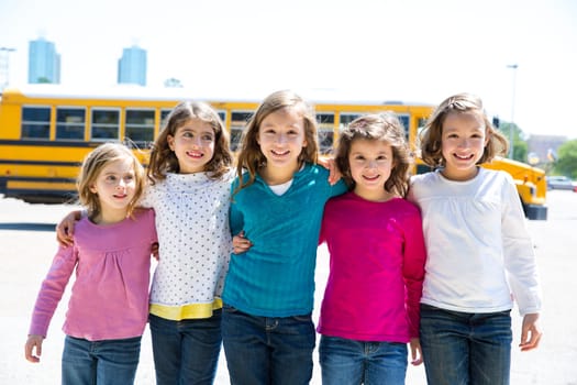 school girls friends sisters in a row walking from yellow school bus lot
