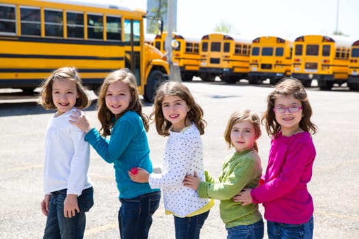 school girls friends sisters in a row walking from yellow school bus lot