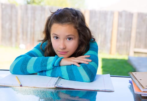 American latin teen girl relaxed on table doing homework on backyard