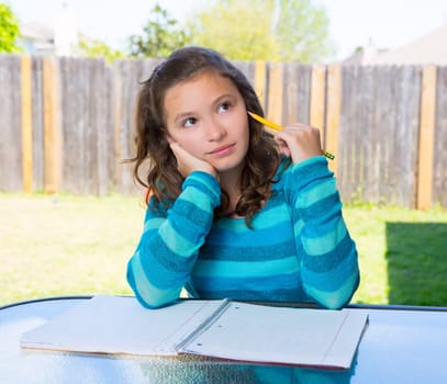 American latin teen girl thinking with pencil doing homework on backyard