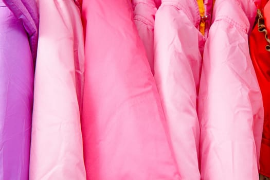 a lot of bright children's clothing on a hanger in the store
