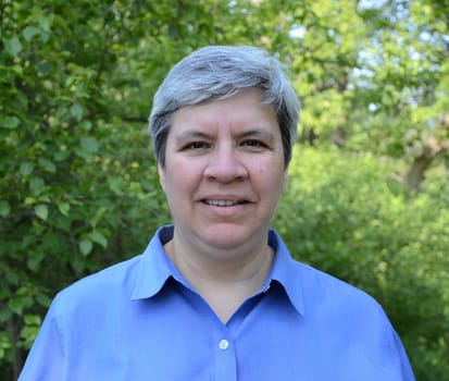 Middle aged woman looking directly at camera, in garden
