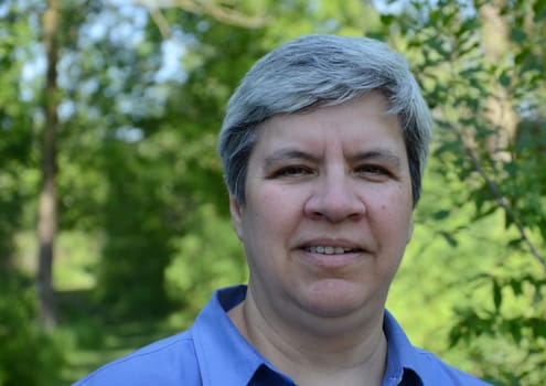 Close up of middle aged woman looking directly at camera, in garden
