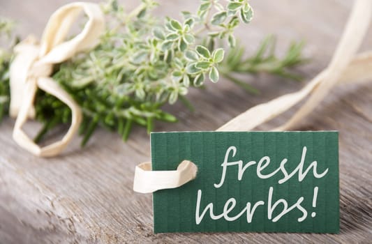 a green label with fresh herbs on it with herbs and wood background