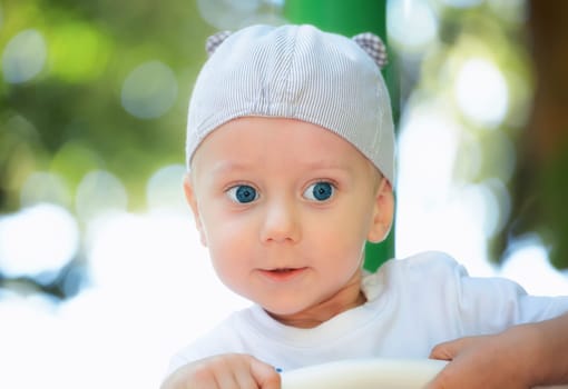 Baby boy portrait with blue eyes outdoor at the playground.