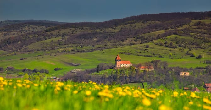 Overcast landscape over the Transylvanian village of Rodbav with the church on the hill, Romania.
