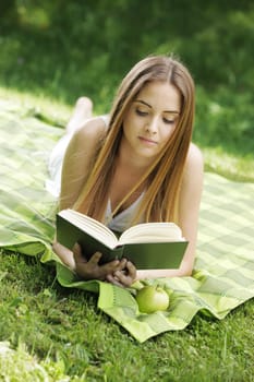 Closeup of a beautiful young woman reading book at park