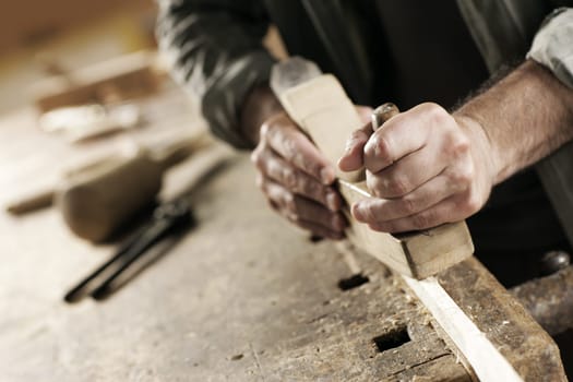 Hands of a carpenter planed wood, workplace