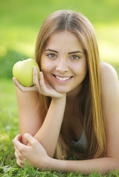 Young smiling woman outdoors holding an apple
