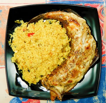 rice side dish with the fried fish on a black square plate