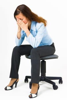 Stress. Woman hides her face in her hands while sitting on an office chair