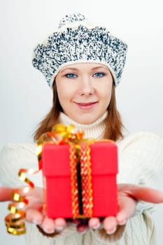 Attractive girl in winter hat gives a wrapped gift
