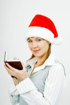 Attractive young girl with a notebook in santa hat