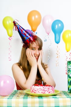 Birthday. The girl at the holiday table with the cake make a wish.