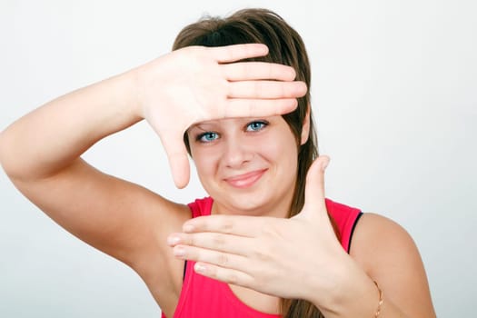 blue-eyed teen girl looks through a framework of hands