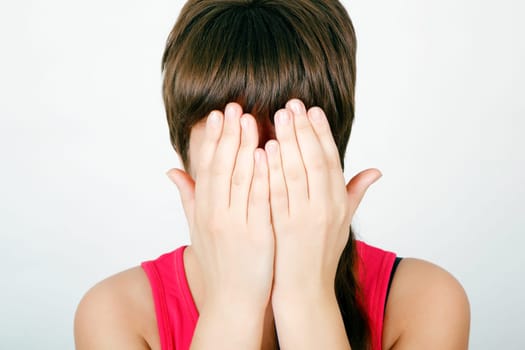 teen girl covers her face with both hands