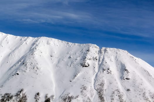 northern mountains covered with snow against a blue winter sky