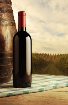 red wine bottle and wodden barrel, vineyard on background