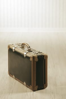 Old-fashioned suitcase alone in a room or station.